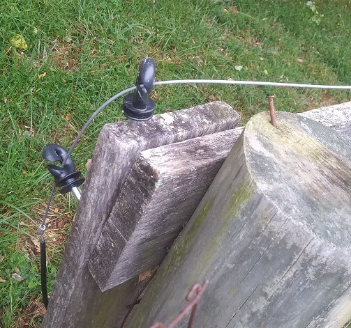 Several black zareba screw-in insulators guide wire around an electric fence segment