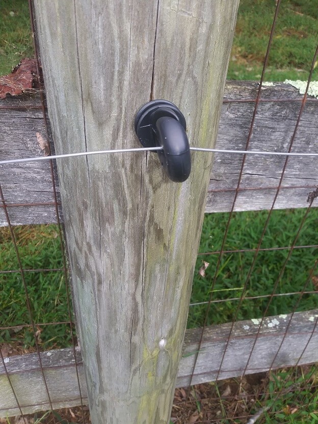 heavy duty black screw-in insulator mounted on a wood post with hot wire.  This is an easy way to fix electric fence problems.